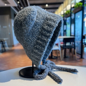 Dettaglio del cappello in maglia grigia con orecchie da orso e lacci caldi lunghi