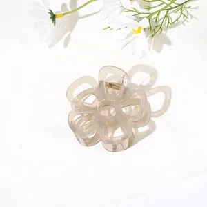 Close-up of minimalist translucent flower hair claw clip with golden metal spring