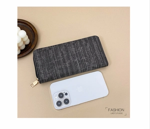 Detailed view of grey textured long zip-around purse compared with a smartphone size