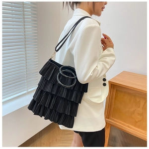 Detail view of black pleated tiered tote bag with unique circular double handles