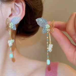 Detail of elegant butterfly tassel earrings with blue stones and pearls on model