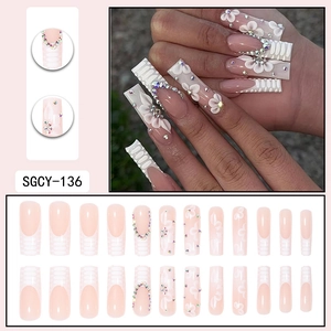 French tip press-on nails in nude pink with 3D white flowers and iridescent rhinestones