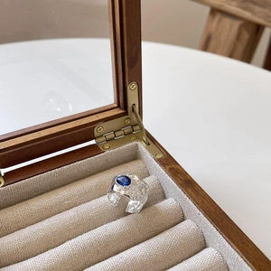 Close-up of irregular hammered silver ring with blue oval stone in a wood jewelry box