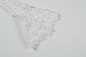 Detail of bell sleeves with floral lace pattern and scalloped edges on white dress