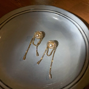 Detail of elegant gold tassel earrings with white pearls and shimmering rhinestones