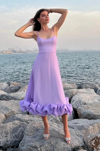 Detailed view of lavender strapless dress with ruffled hem against ocean background