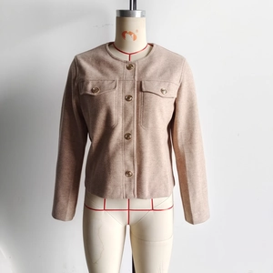 Close-up of beige tweed jacket featuring textured wool fabric and gold metal buttons
