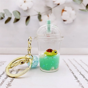 Detail of acrylic milk tea cup keychain featuring a floating turtle in green liquid