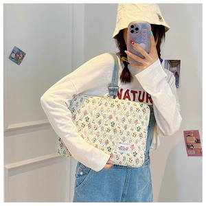 Quilted floral laptop sleeve shown with model, featuring HELLO EVERYTHING GOOD LUCK label