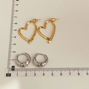Detailed size comparison of 18K gold heart hoops and silver textured earring studs