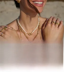 Close-up of emerald zircon and pearl gold jewelry set on model with beach vibes