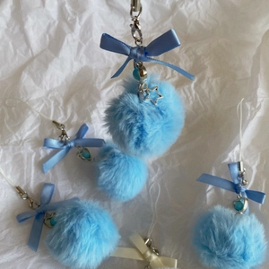 Macro detail of soft light blue plush pompom keychain with satin bow and metal star charm