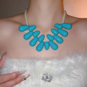 Gros plan du collier ras du cou avec perles gouttes turquoise et perles blanches