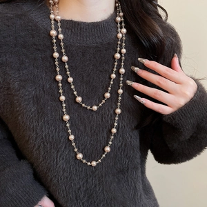 Close-up of double-layer champagne pearl necklace with crystals on brown sweater