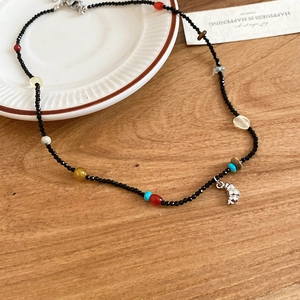 Detail of beaded necklace with colorful stones and silver elephant pendant on wood