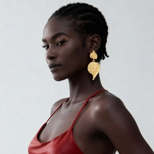 Close-up of a model wearing golden leaf-shaped earrings with unique metal texture