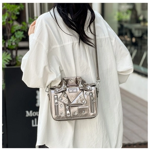 Detail of silver motorcycle jacket crossbody bag with rivets and zipper hardware