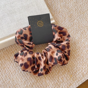 Detail of leopard print fabric scrunchie on beige linen with handmade label tag