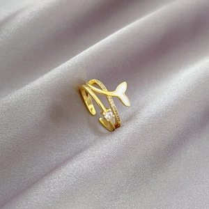 Adjustable gold mermaid tail ring featuring white enamel and a sparkling zircon stone