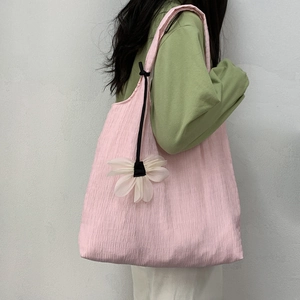 Detailed close-up of pink pleated tote bag texture and cute white flower pendant charm