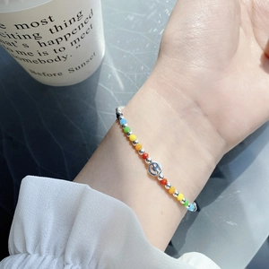 Detail of a colorful beaded rainbow bracelet featuring a silver smiley face charm pendant