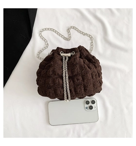 Flat lay of brown quilted chain bag with drawstring closure next to a smartphone