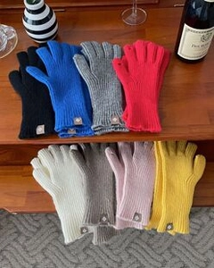 Detailed assortment of colorful knitted gloves arranged on a wooden rustic staircase