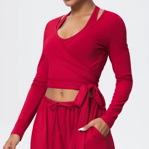 Detail of red workout set featuring long sleeve V-neck cross strap top and yoga pants