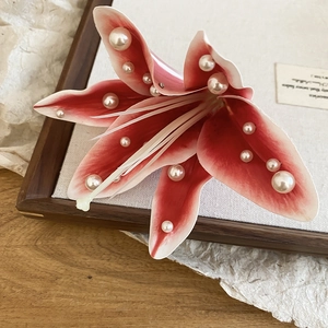 Vue détaillée d'une élégante barrette fleur de lys en tissu rouge avec des perles