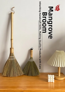 Detail view of handmade miscanthus broom set with natural bamboo handles on a wooden table
