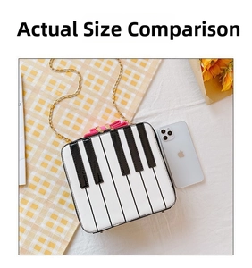 Close-up of piano key crossbody bag with pink bow and gold chain next to a phone