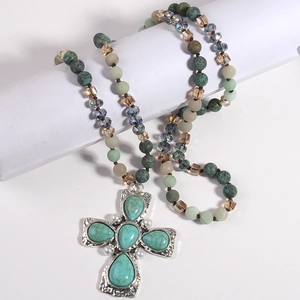 Dettaglio macro della collana boho con grande pendente a croce e perline turchesi decorative