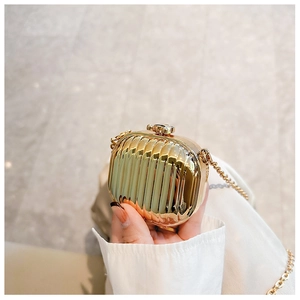 Detail of a mini golden acrylic suitcase bag with ripple texture and chain strap
