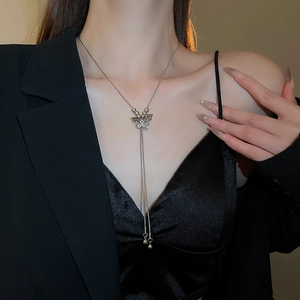 Detailed view of silver butterfly pendant with long chain tassels worn by a model