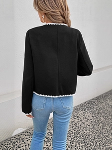 Back view of a black French style knit jacket with white wavy trim and textured fabric