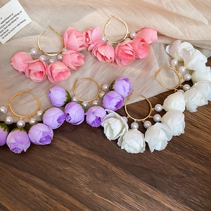 Detail of floral hoop earrings with silk roses and faux pearls in pink and purple colors