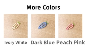 Three carrot-shaped hair clips in ivory, deep blue, and rose pink on a wooden surface