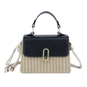 Close-up of contrast stitching on leather and woven straw bag with golden lock
