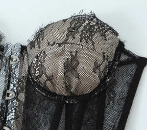 Macro shot of black floral lace fabric and silver metal buckles on a corset top