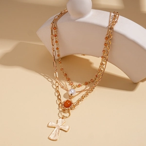 Collana a strati dorata con croce, perle acriliche e gemme su supporto bianco elegante