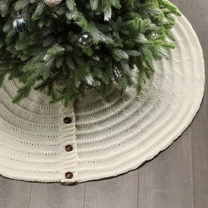 Detail of cream white knitted Christmas tree skirt with decorative brown wood buttons