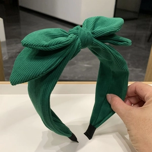 Detail of green oversized bow headband featuring textured fabric and non-slip ends
