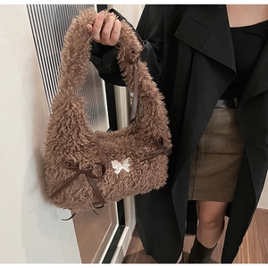 Detail of plush brown teddy bag featuring leather bows and a white butterfly charm