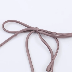 Detailed close-up of dusty pink satin tie and bow with refined stitching on midi dress