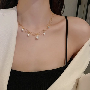 Detail view of multi-layer gold plated necklace with five elegant white pearls on model