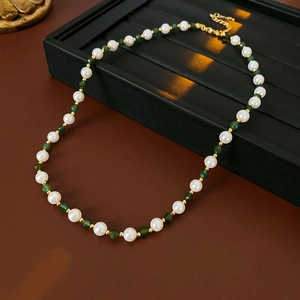 Detail of vintage beaded necklace with white pearls, green stones and gold spacers