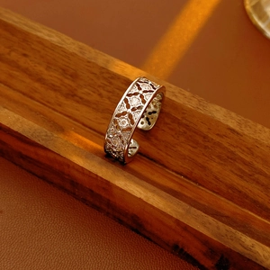 Detailed macro of silver plated hollow flower ring with cubic zirconia on wood
