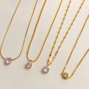 Collection of four gold-plated necklaces with round zircon pendants on varied chains