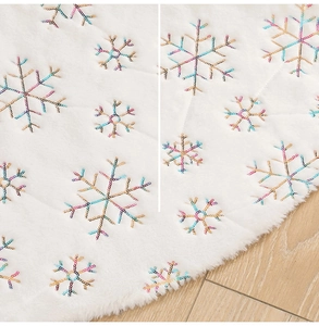 Detail of white plush Christmas tree skirt featuring colorful sequin snowflake embroidery