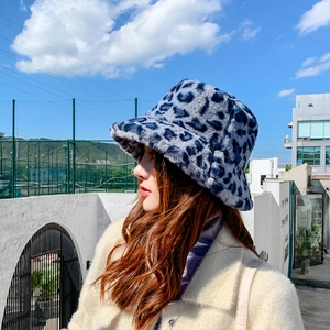Blue leopard faux fur bucket hat shown with stylish winter outfit on a model outdoors